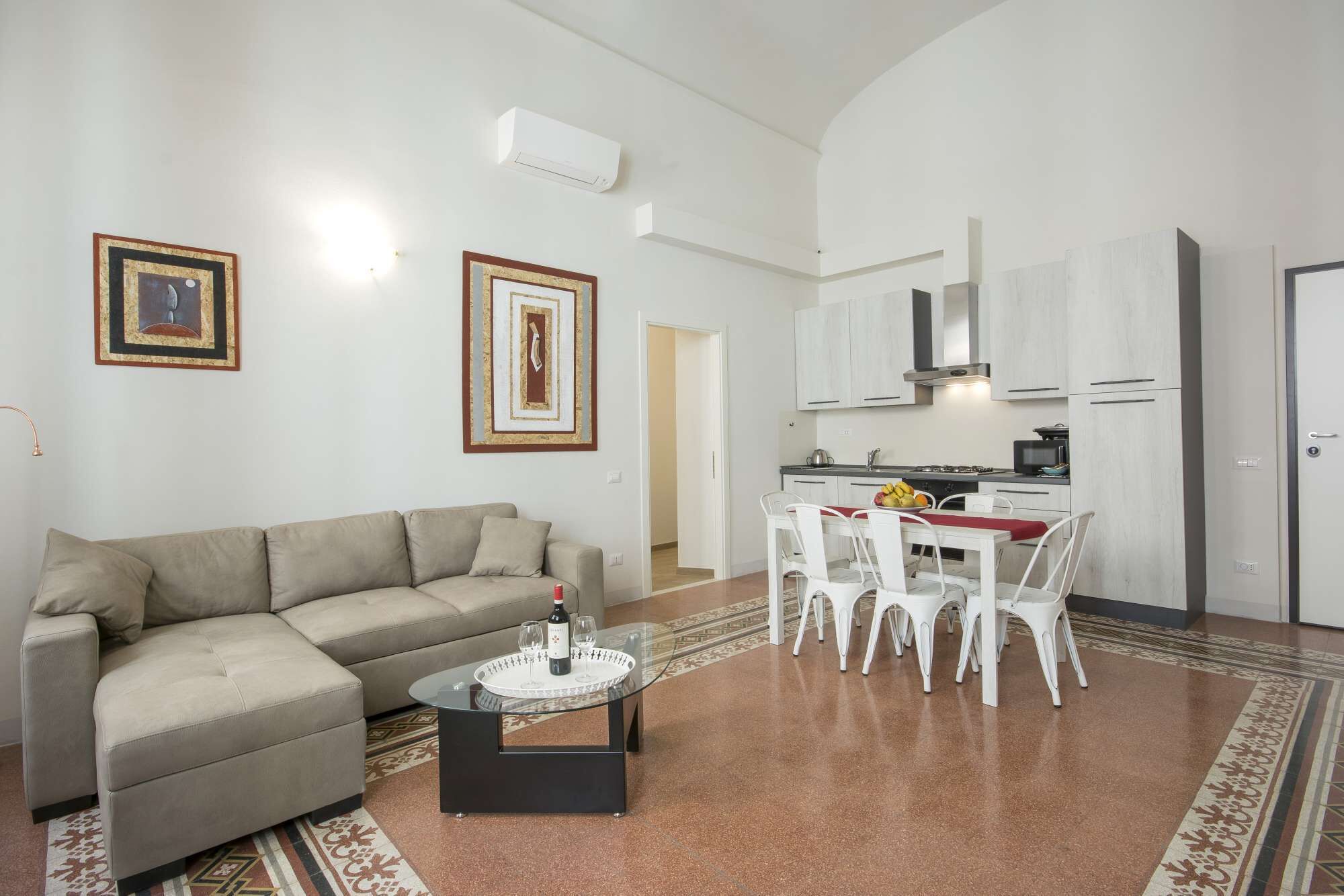 A living room with a sofa, a glass coffee table, and a dining area with chairs and a table.