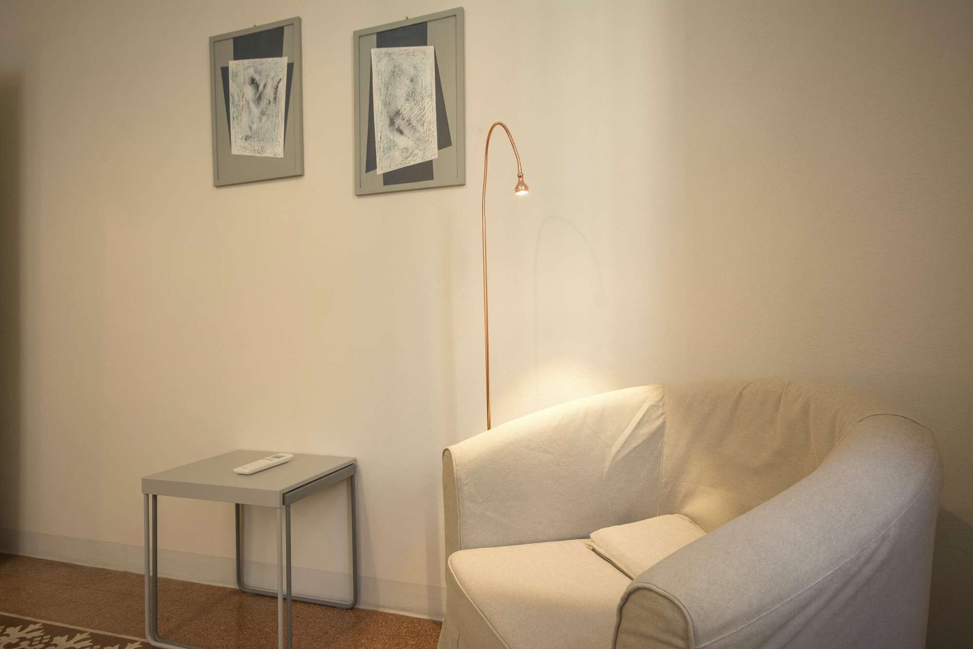 A minimalist room with a sofa, a small table, and two framed artworks on the wall.