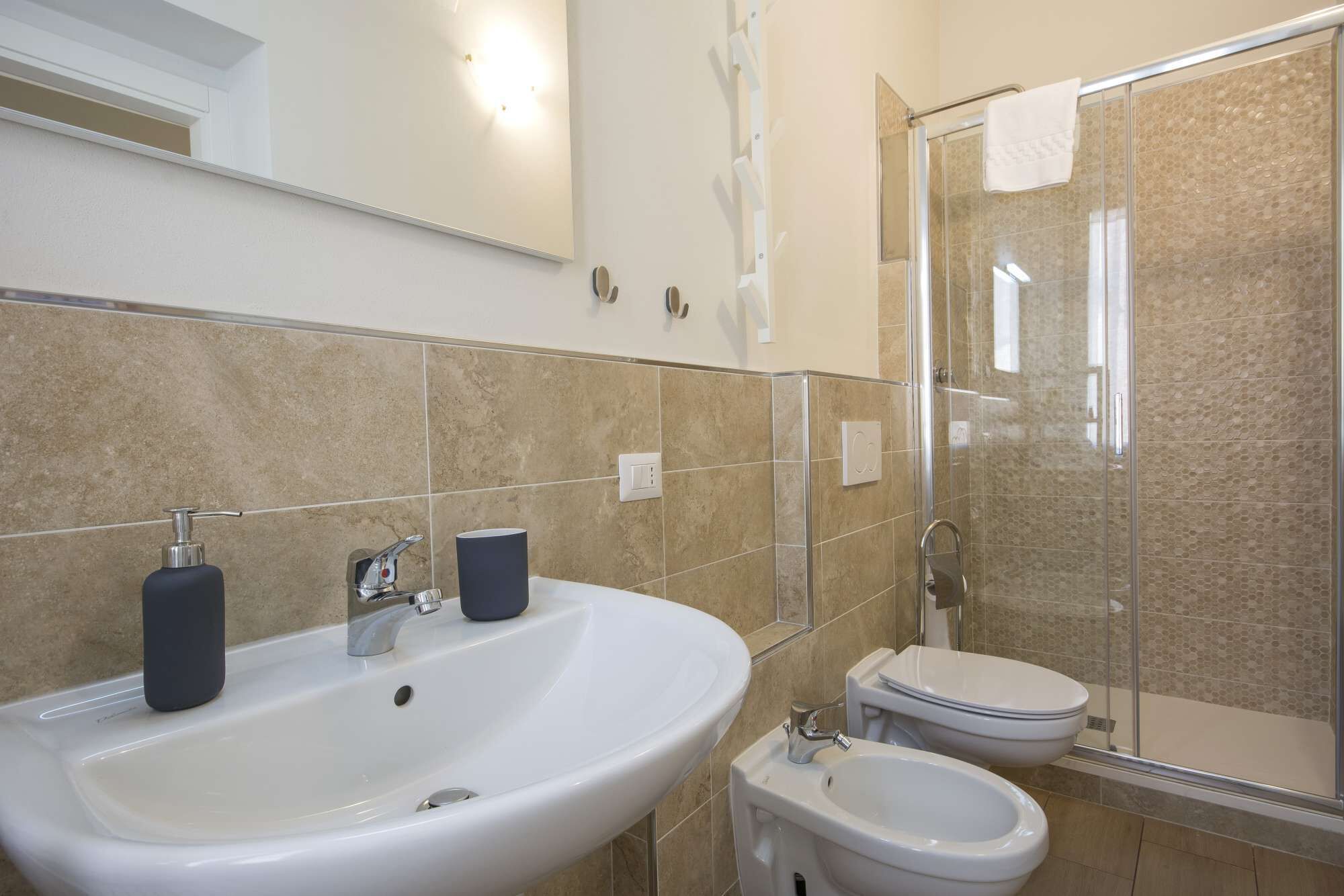 A bathroom with a large sink, a bidet, and a glass-enclosed shower.