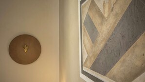 Eine Wand mit einem runden Metallobjekt und einem geometrischen Wandbild.