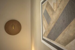 Eine Wand mit einem runden Metallobjekt und einem geometrischen Wandbild.