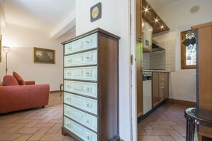 A living room with a sofa, a cabinet, and a kitchen area with cabinets and a stove. - BIG Apt with Garden · Super Central Tuscan style (Siena)