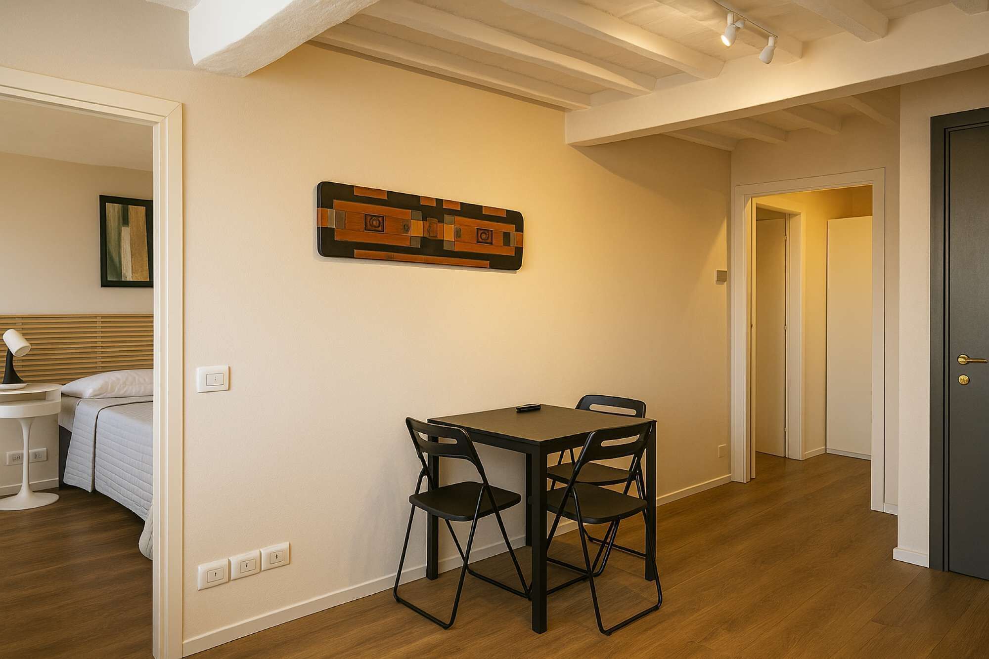 A room with a table and chairs, a bed, and a door.