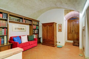 A library with bookshelves, a red sofa, and a wooden cabinet. - A BALCONY ON THE PIAZZA OF THE PALIO (Siena)
