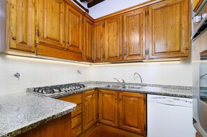 A kitchen with wooden cabinets, a granite countertop, a stainless steel sink, and a dishwasher. - A BALCONY ON THE PIAZZA OF THE PALIO (Siena)