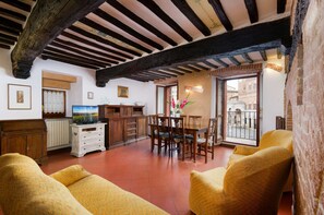 A room with a dining area, a television, and a view of the street. - A BALCONY ON THE PIAZZA OF THE PALIO (Siena)