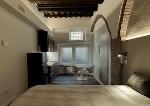 A compact bedroom with a bed, a kitchenette, and a small dining area with two chairs. - Very Central Studio close to public parking and il Campo (Siena)