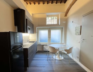 A compact kitchen with a refrigerator, cabinets, and a window overlooking a garden. - Very Central Studio close to public parking and il Campo (Siena)