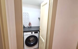 A laundry area with a washing machine and an iron on a countertop. - Very central studio II close to public parking and il Campo (Siena)