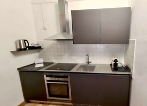 A compact kitchen with a built-in oven, a sink, and a stove. - Very central studio II close to public parking and il Campo (Siena)
