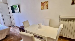 A room with a white table, two chairs, a radiator, and a wall-mounted artwork. - Very central studio II close to public parking and il Campo (Siena)