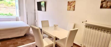 Une pièce comprenant un lit, une table avec des chaises, un radiateur et des œuvres d’art accrochées aux murs.