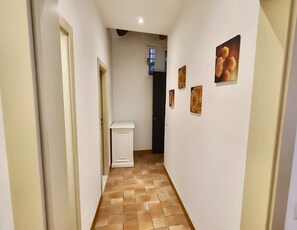 A narrow hallway with a tiled floor, white walls, and a door at the end. - Very central studio II close to public parking and il Campo (Siena)