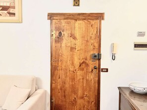 Eine Holztür mit Riegel, ein an der Wand montiertes Telefon und ein gerahmtes Bild darüber.
