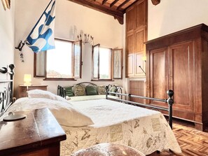 Ein Schlafzimmer mit einem Bett, einem Holzschrank, einem Fenster mit Vorhängen und einer Flagge.