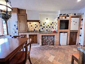 Eine Küche mit Steinboden, Holzschränken, einem eingebauten Backofen und einem Kühlschrank.