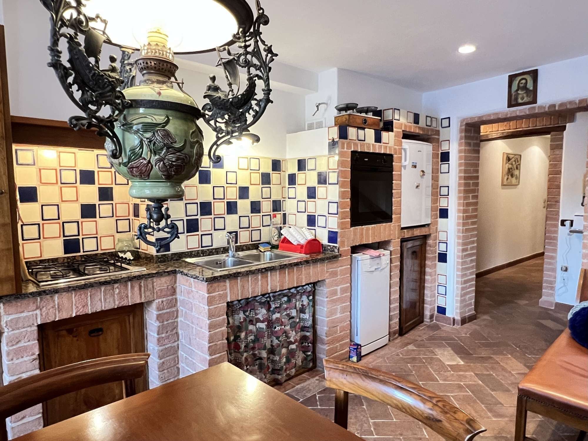A kitchen with a tiled backsplash, a gas stove, a sink, and a refrigerator.