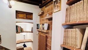 A room with a fireplace, bookshelves, a radiator, and a wooden cabinet. - A BALCONY ON THE PIAZZA OF THE PALIO (Siena)