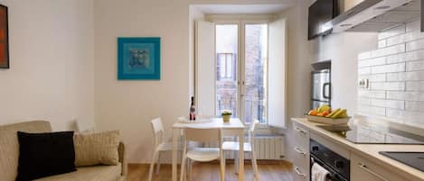 A compact living space with a kitchenette, a dining area, and a sofa.