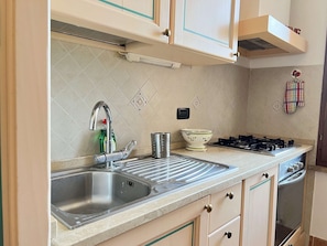 A kitchen with a double sink, stainless steel faucet, a gas stove, and a microwave. - Cozy Studio 8 in the Heart of Siena (Siena)