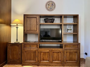 A wooden entertainment center with a flat-screen TV, drawers, and shelves. - Cozy Studio 8 in the Heart of Siena (Siena)