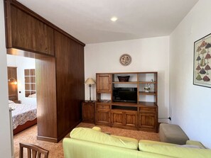 A living room with a wooden cabinet, a television, and a lamp. - Cozy Studio 8 in the Heart of Siena (Siena)