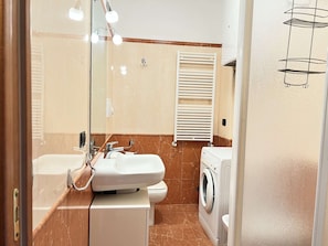 A bathroom with two sinks, a mirror, a towel rack, a toilet, and a washing machine. - Cozy Studio 8 in the Heart of Siena (Siena)