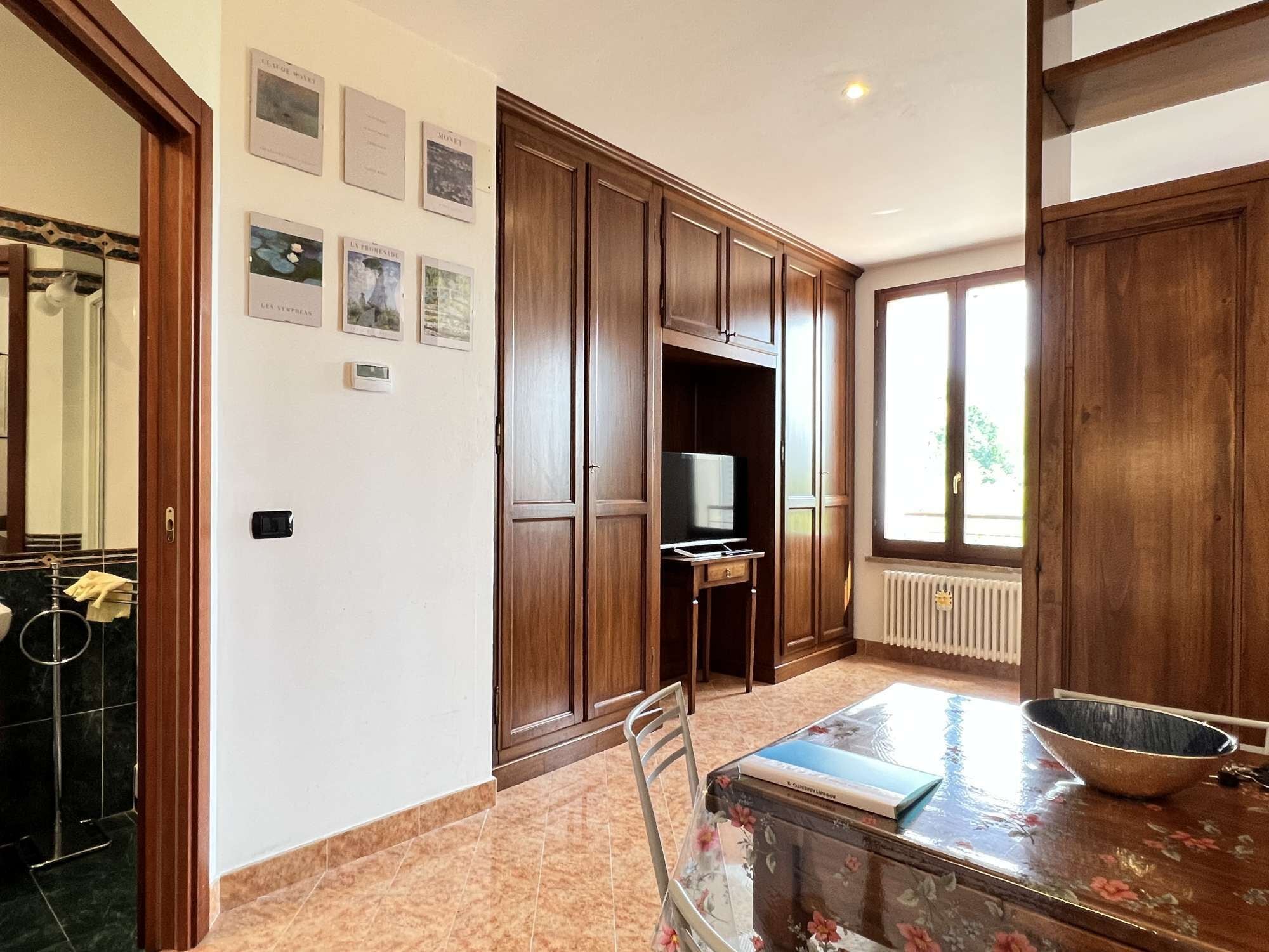 Una cucina con mobili in legno, un tavolo da pranzo con sedie, una televisione e una finestra con vista.