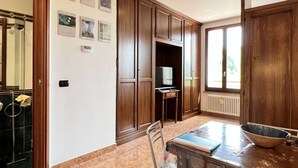 A kitchen with wooden cabinets, a dining table with chairs, a television, and a window with a view. - Cozy Studio 8 in the Heart of Siena (Siena)