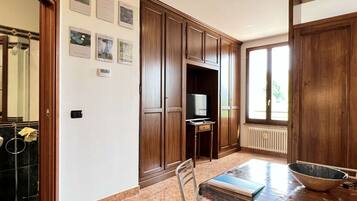 Una cucina con mobili in legno, un tavolo da pranzo con sedie, una televisione e una finestra con vista.