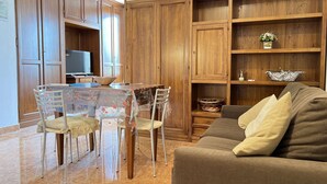 A living room with a brown sofa, a dining table with chairs, wooden cabinets, and a television. - Cozy Studio 8 in the Heart of Siena (Siena)