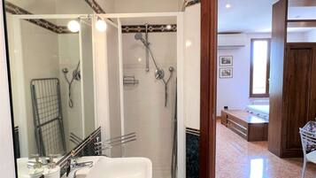 Un bagno con doccia, lavandino e specchio.