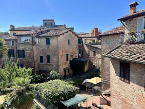 A narrow street with traditional stone buildings, a small courtyard with a table and chairs, and a palm tree. - Astonish cathdral view, Super central (Siena)
