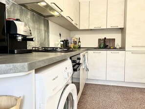 A compact kitchen with a washing machine, a coffee maker, and a stove. - Astonish cathdral view, Super central (Siena)