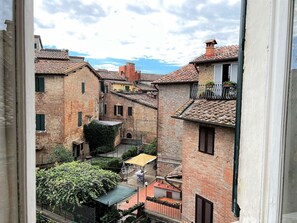 A narrow street with traditional brick buildings, a small courtyard, and a view through a window. - Astonish cathdral view, Super central (Siena)
