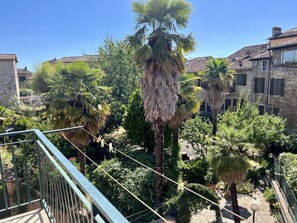 A balcony with a view of a garden, including palm trees and a stone building. - Astonish cathdral view, Super central (Siena)