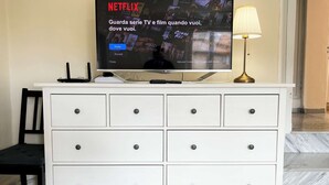 Ein Fernseher auf einem weißen Schrank mit Schubladen, einer Lampe und einer Fernbedienung.