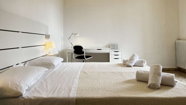 Ein Hotelzimmer mit Bett, Schreibtisch, Stuhl, Lampe und Handtüchern.