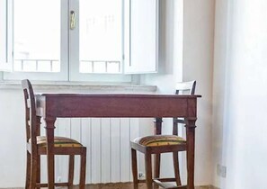 A dining table with two chairs in front of a window with white shutters. - Apartment in Piazza del Campo area 3 bedrooms 2 bathrooms (siena)