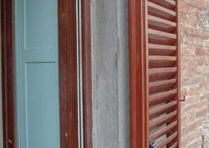 A door with a vertical wooden frame and a window with horizontal blinds. - Apartment in Piazza del Campo area 3 bedrooms 2 bathrooms (siena)