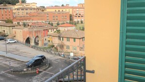 A balcony with a view of a cityscape, including buildings and a roundabout. - A BALCONY ON THE PIAZZA OF THE PALIO (Siena)