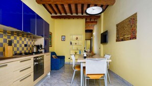 A compact kitchen with modern appliances, a dining area with a table and chairs, and a blue sofa. - A BALCONY ON THE PIAZZA OF THE PALIO (Siena)