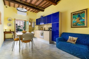 A compact living space with a dining area, kitchenette, and a sofa. - A BALCONY ON THE PIAZZA OF THE PALIO (Siena)