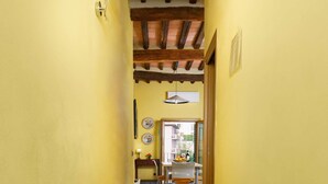 A hallway with yellow walls, a wooden ceiling, and a tiled floor. - A BALCONY ON THE PIAZZA OF THE PALIO (Siena)