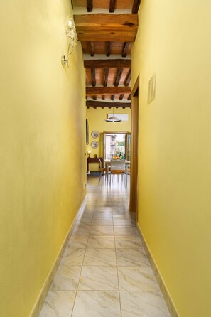 A hallway with yellow walls, a wooden ceiling, and a tiled floor. - A BALCONY ON THE PIAZZA OF THE PALIO (Siena)
