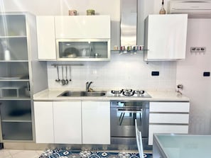 A modern kitchen with white cabinets, a stainless steel sink, a gas stove, and a dishwasher. - A BALCONY ON THE PIAZZA OF THE PALIO (Siena)