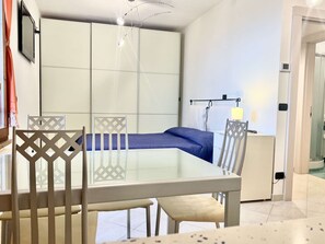 A compact bedroom with a bed, a small table, and chairs. - A BALCONY ON THE PIAZZA OF THE PALIO (Siena)
