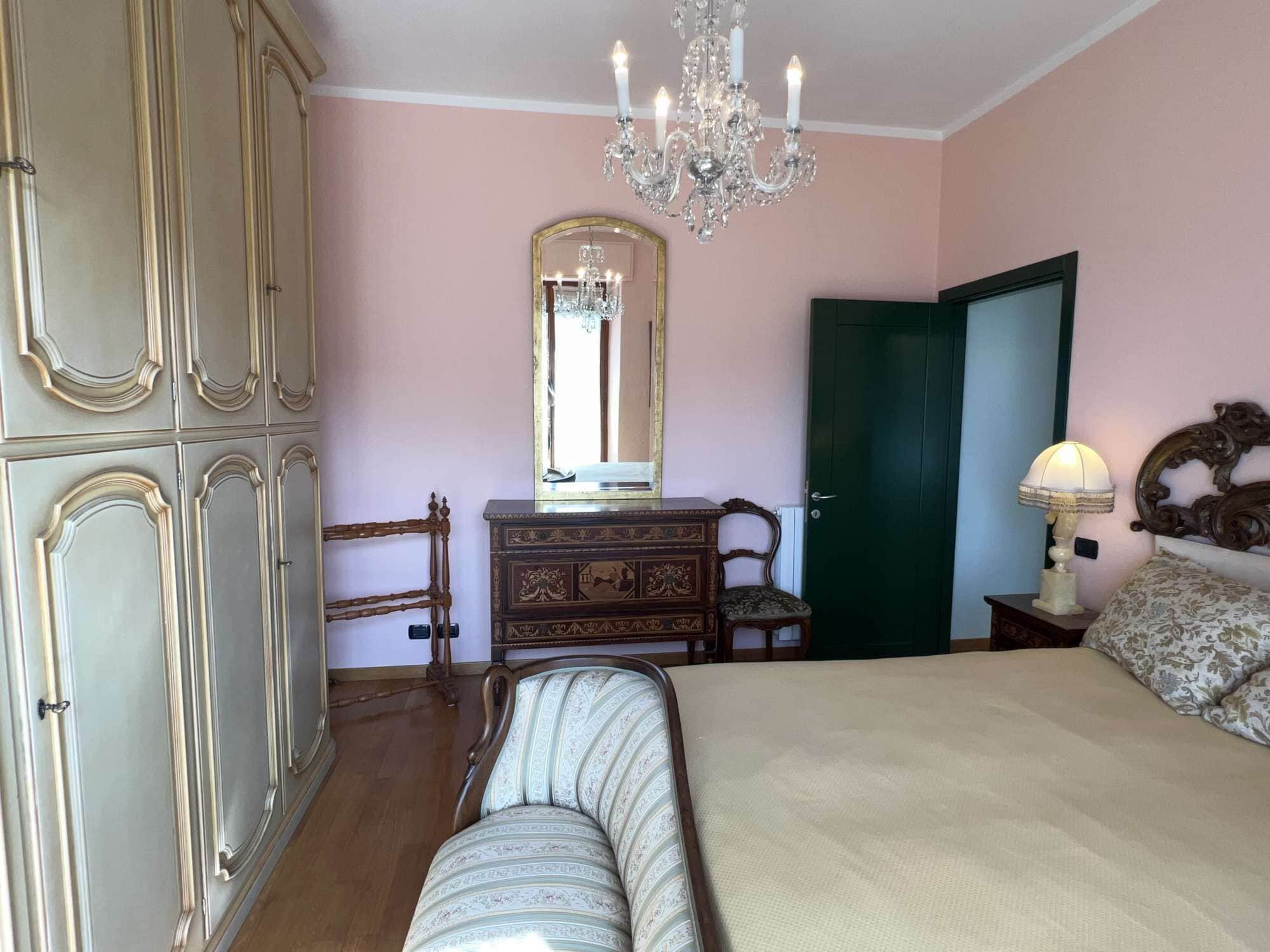 Una camera da letto con un letto, una cassettiera, uno specchio e un lampadario.