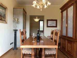 Ein Esszimmer mit einem Holztisch, Stühlen, einer Kristallleuchtre und Kunstwerken an den Wänden.
