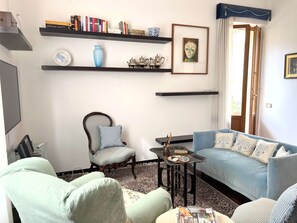 Un soggiorno con divano, poltrone, tavolino e libreria.